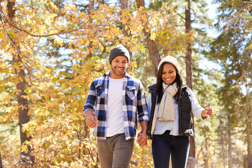 A couple in their mid-30s walks amid the forest while enjoying Fall in Leavenworth, WA.